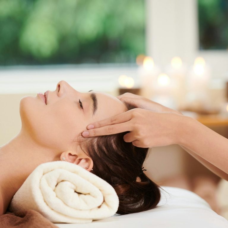 Woman relaxed and serene on a massage bed, receiving a Japanese acupressure point facial massage.